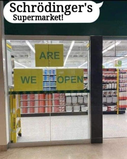 Supermarket window has 3 words, separated by 3 pieces of paper. The papers reading "We" and "Open" are on the same level. Between them, higher up, is "Are". How to read is ambiguous. It can be "We are open" or "Are We Open". The caption is  Shrodenger's Supermarket